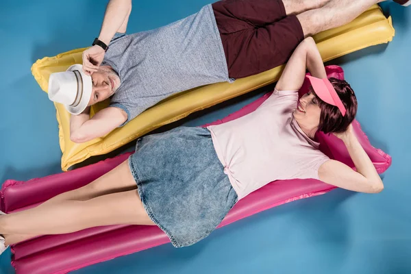 Elderly couple lying on swimming mattresses — Stock Photo, Image