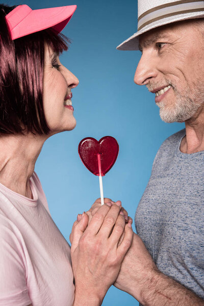 elderly couple holding hands with lollipop