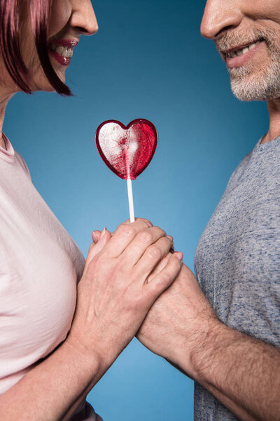 elderly couple holding hands with lollipop