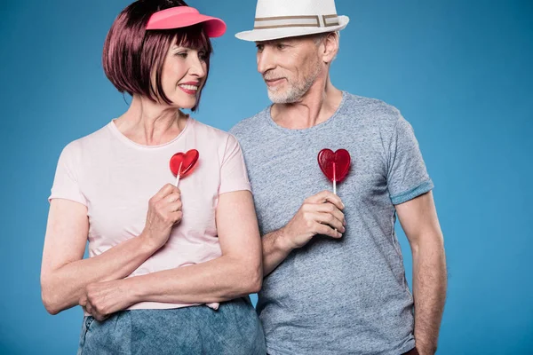 Fashionable elderly couple holding lollipops — Stock Photo, Image