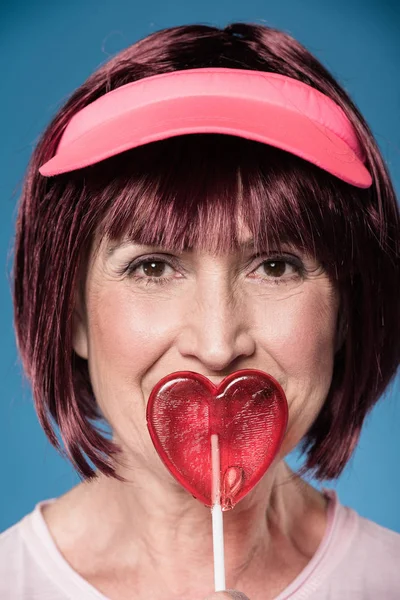 Woman licking lollipop in form of heart — Stock Photo, Image