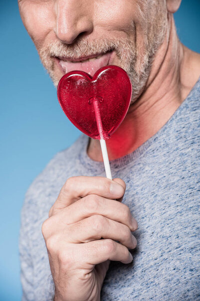 man licking lollipop in form of heart