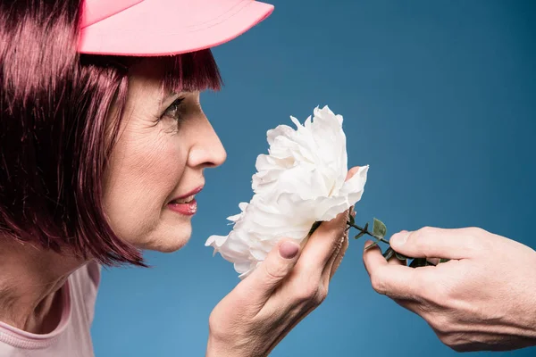 Красива літня жінка пахне квіткою — стокове фото