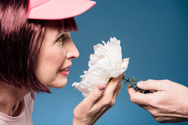 beautiful elderly woman smelling flower