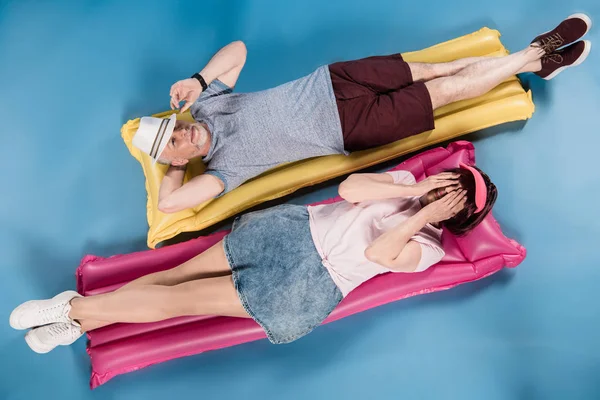 Elderly couple lying on swimming mattresses — Stock Photo, Image