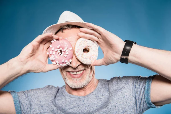 Homem segurando donuts na frente dos olhos — Fotografia de Stock