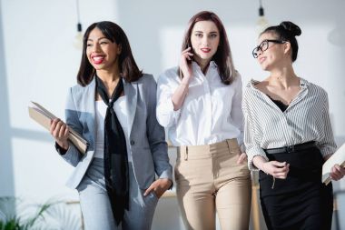 young multiethnic businesswomen walking at office clipart