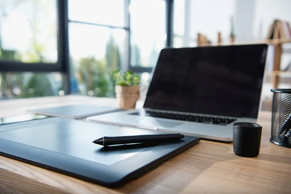 Portátil con gráficos tableta en la mesa en la oficina —  Fotos de Stock