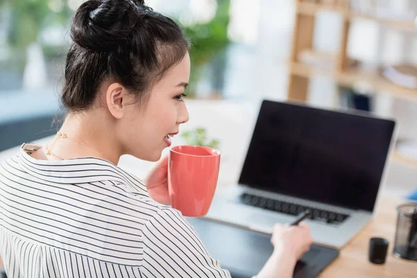 Asiático diseñador beber café mientras trabajo —  Fotos de Stock