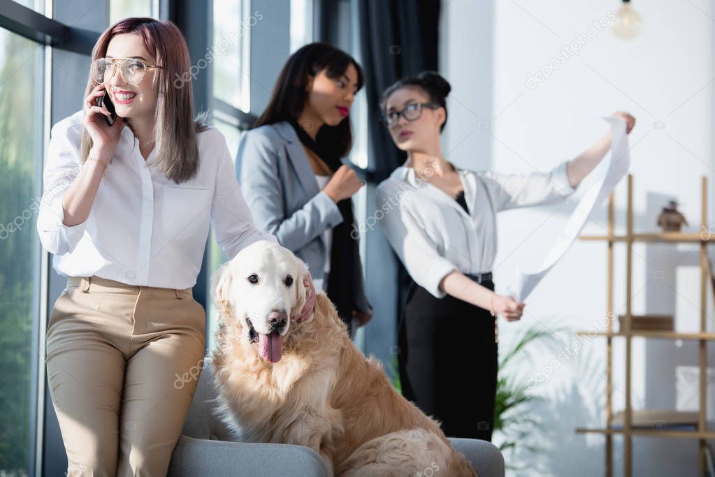 businesswoman talking on smartphone while petting dog