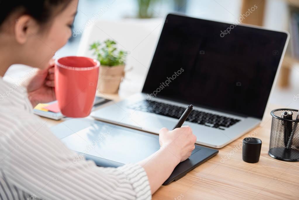 asian designer drinking coffee while working