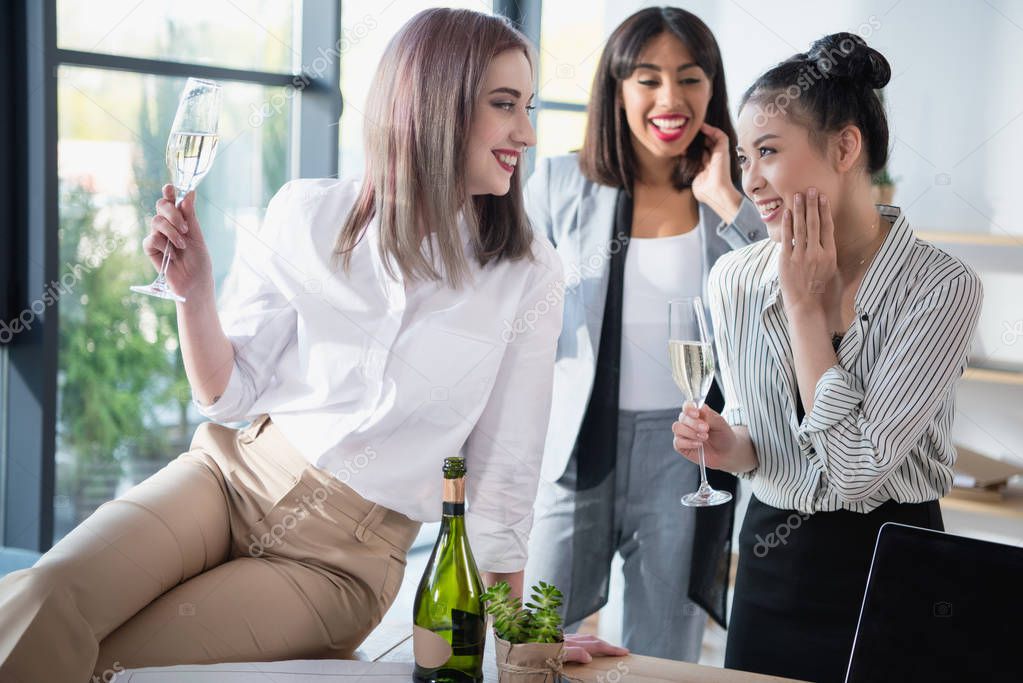 multiethnic businesswomen smiling and drinking champagne