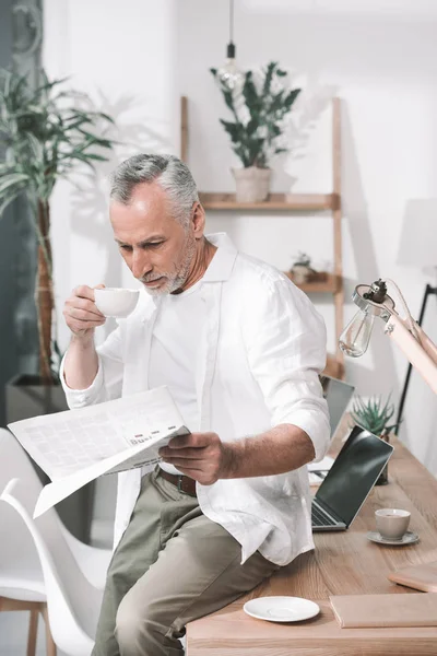 Empresario tomando café y leyendo el periódico — Foto de Stock