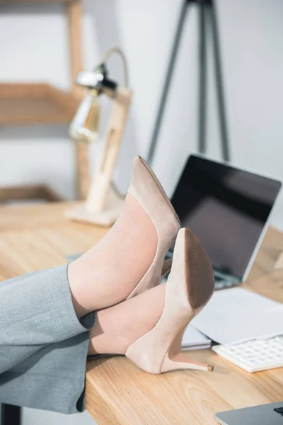 Womens legs in stilettos on table — Stock Photo, Image