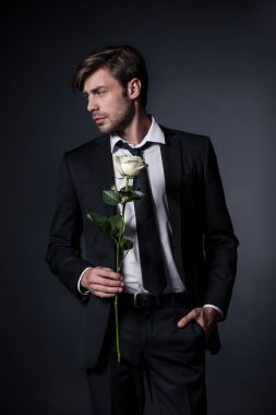 man in formal wear holding rose