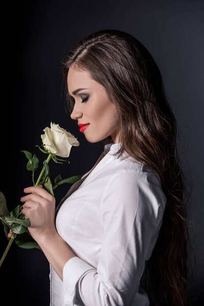 woman smelling rose with eyes closed