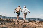 starší pár kráčející na pláži 
