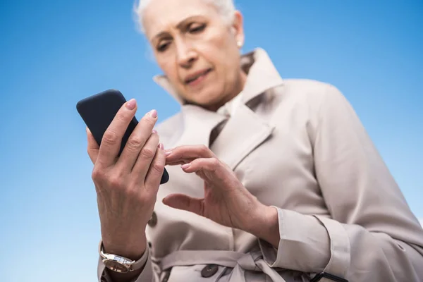 Szürke hajú nő használ smartphone — ingyenes stock fotók