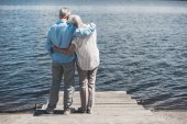 Seniorenpaar umarmt sich am Ufer