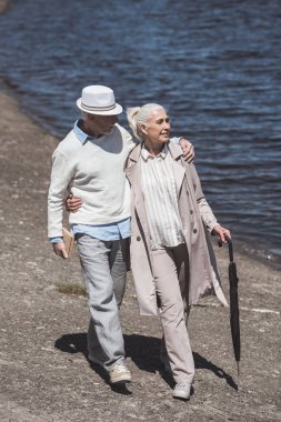 senior couple walking on river shore clipart