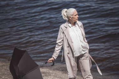 woman walking with umbrella on river shore clipart