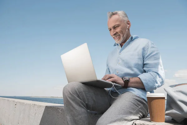Grey haired man typing on laptop — Stock Photo, Image