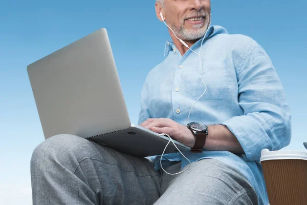 Äldre man som arbetar på laptop utomhus — Stockfoto