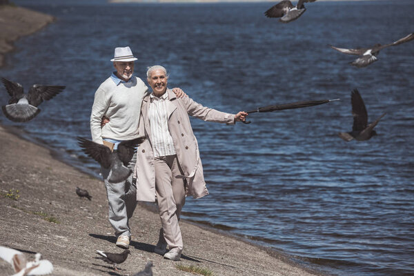 elderly couple walking on river shore