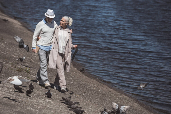 пожилая пара прогуливаясь по берегу реки
