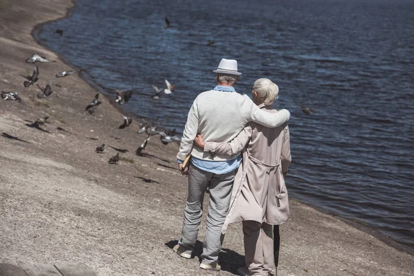 Senior couple walking on river shore — Stock Photo, Image