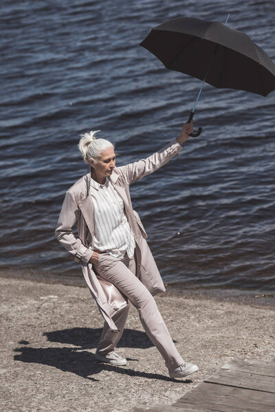 woman walking with umbrella on river shore