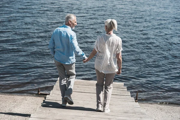 Casual pareja de ancianos caminando a orillas del río — Foto de Stock