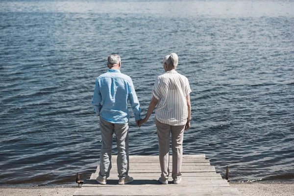 Пожилая пара, стоящая на берегу реки днем — стоковое фото