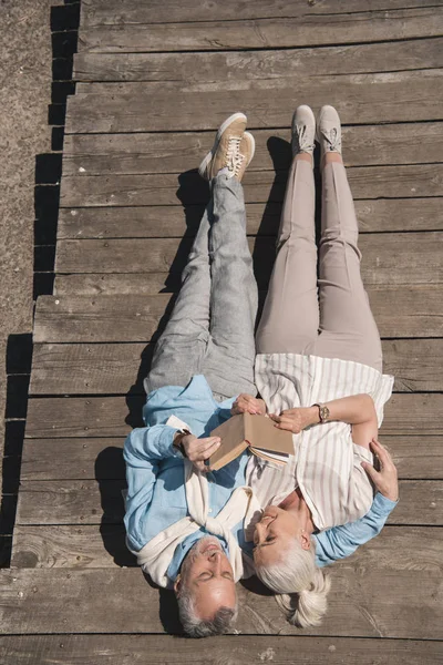 Livro de leitura casal sênior sobre pavimento — Fotografia de Stock
