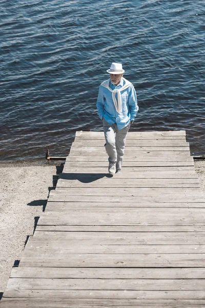 Hombre mayor con estilo caminando a orillas del río — Foto de stock gratis