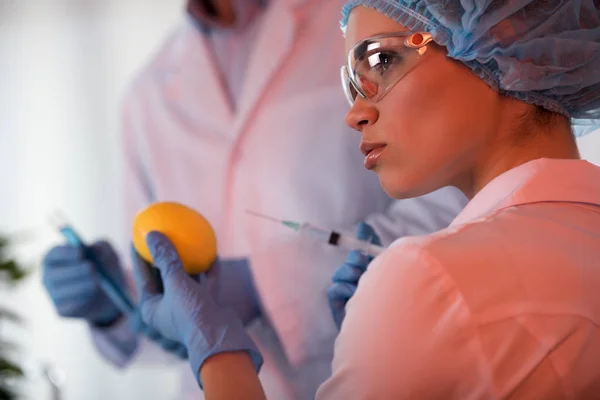 Female scientist holding lemon — Stock Photo, Image