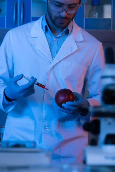 Scientist with syringe and apple — Free Stock Photo