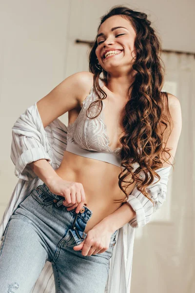 Mulher sorrindo e abotoando jeans — Fotografia de Stock
