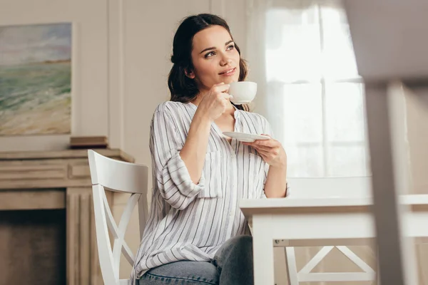 Молода жінка п'є каву вдома — стокове фото