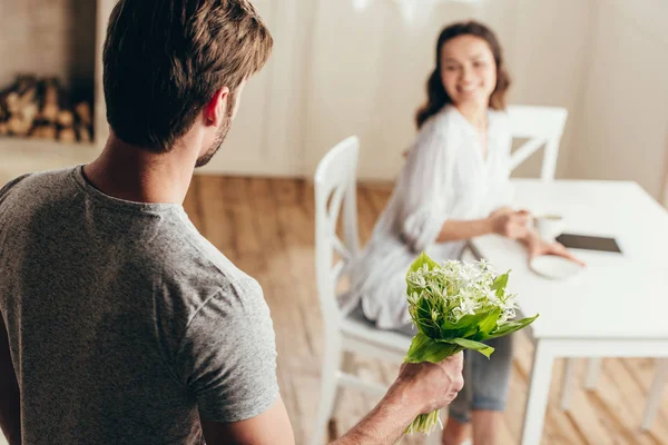 Man presenterar blommor till flickvän hemma — Stockfoto