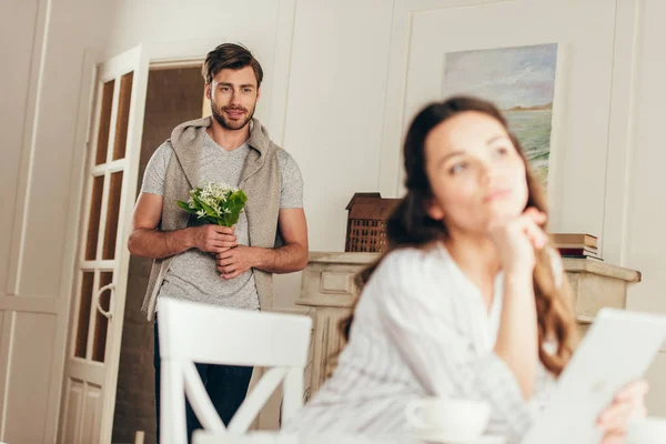 Mannen med bukett blommor tittar på flickvän — Stockfoto