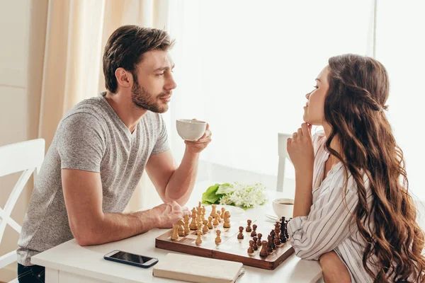 Молодая пара играет в шахматы дома — стоковое фото