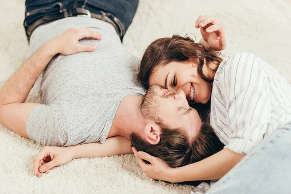 Giovane coppia sdraiata su tappeto a casa — Foto Stock