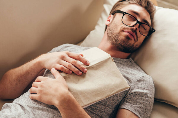 young man sleeping with book at home