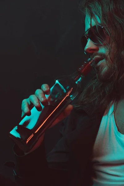 Borracho en gafas de sol bebiendo whisky de la botella — Foto de Stock