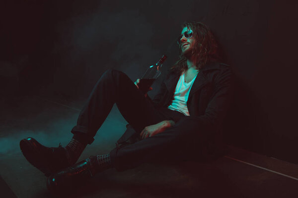 юный пьяница в солнечных очках пьет виски
