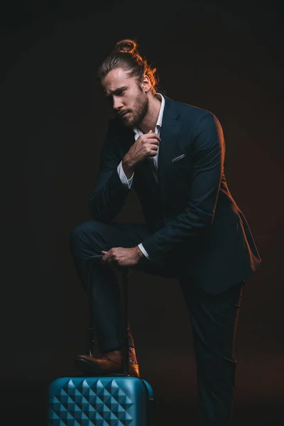 Pensive man in suit leaning on suitcase — Stock Photo, Image