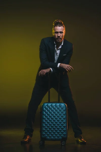 Young man in tuxedo leaning on suitcase — Stock Photo, Image