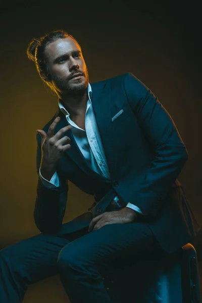 Elegant man in tuxedo sitting on suitcase — Stock Photo, Image