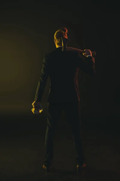 Man in tuxedo holding ax and money — Stock Photo, Image